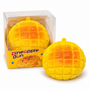 Pineapple bun squishy toy shown unboxed next to its own clear retail packaging