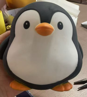 Original supplier photo: Charcoal and white penguin squishy with an orange beak and orange feet