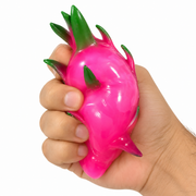 Hand squeezing a glossy pink dragon fruit squishy toy with green leaf details